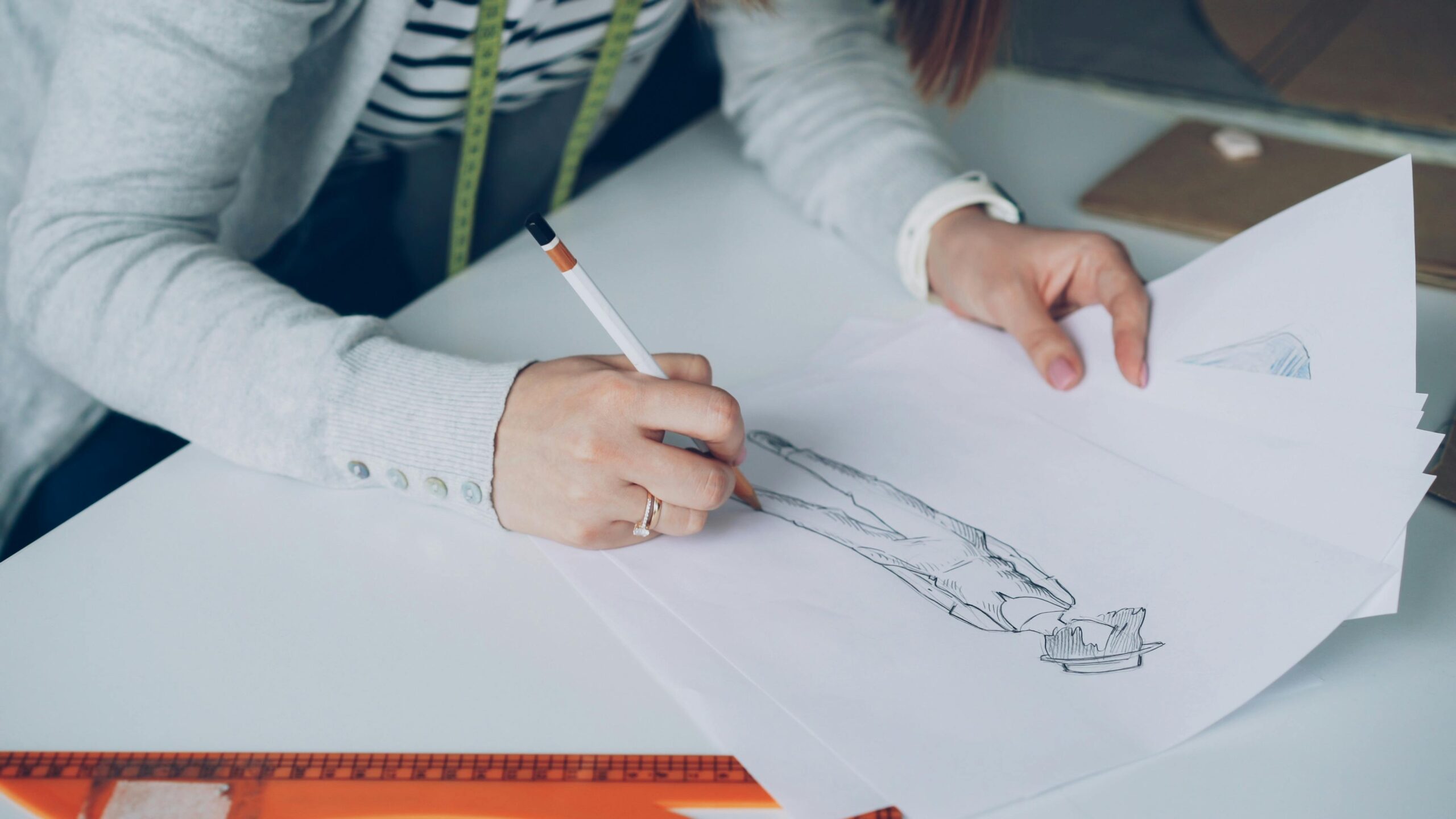 Fashion designer drawing sketches on paper, focusing on creativity and design.